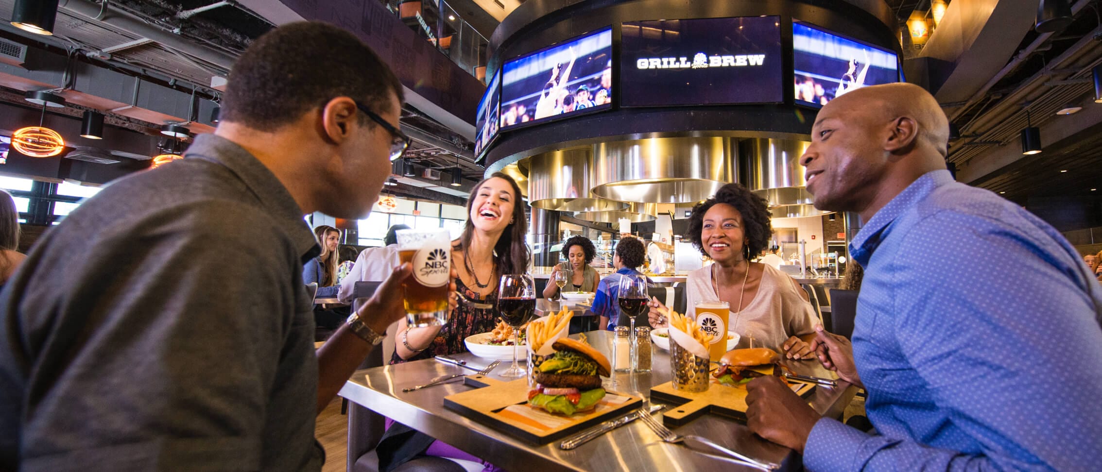 Un grupo de amigos cenan en una mesa cuadrada en NBC Sports Grill & Brew, un restaurante innovador en Universal Orlando's CityWalk.