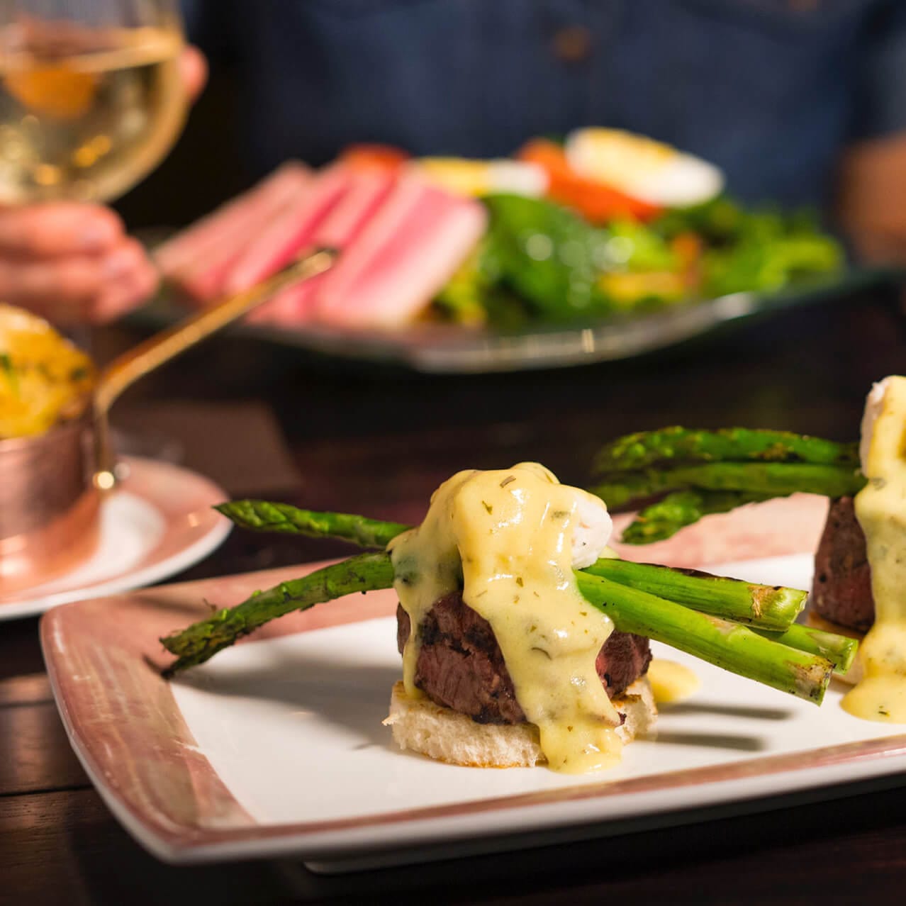 Un plato con bistec decorado con espárragos y una salsa cremosa en Toothsome Chocolate Emporium and Savory Feast Kitchen en Universal CityWalk Orlando.