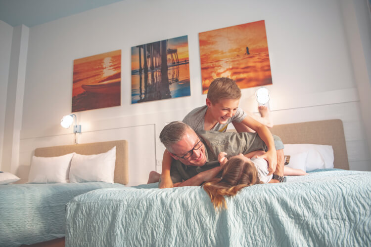 Un padre jugando con sus dos hijos en su habitación de hotel en Universal's Endless Summer Resort: Dockside Inn and Suites.