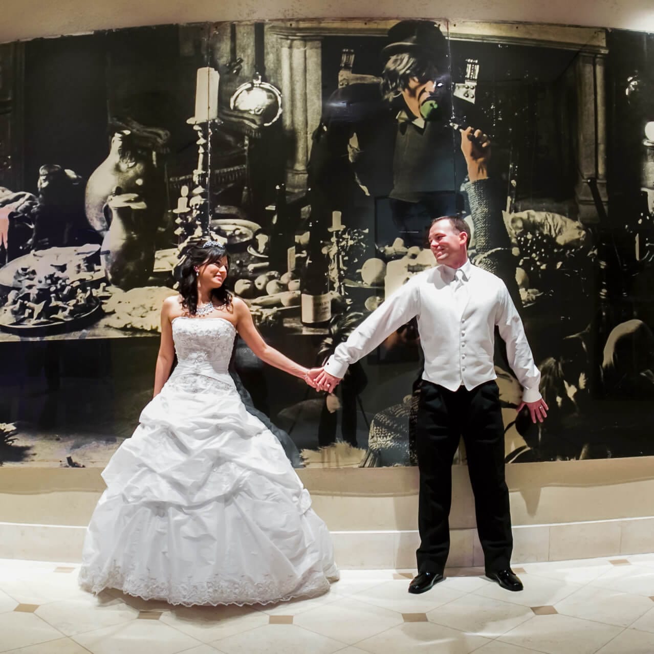 Una pareja de novios tomados de la mano frente a un gran mural en Hard Rock Hotel®, en Universal Orlando.