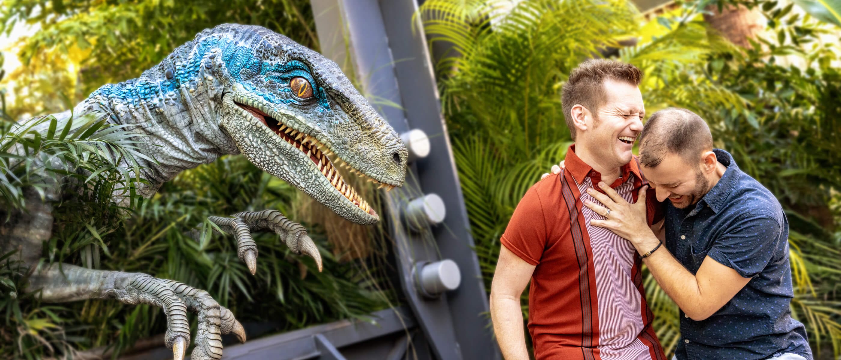 Una pareja abrazándose y riendo con alivio después de haber sido asustados por Blue, la Velociraptor, que aún acecha cerca.