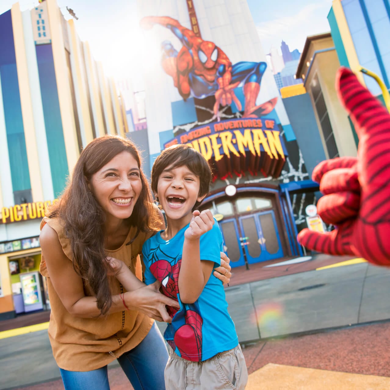 Una mamá y su hijo sonríen y se ríen frente a la atracción The Amazing Adventures of Spider-Man® en Marvel Super Hero Island® de Islands of Adventure en Universal.