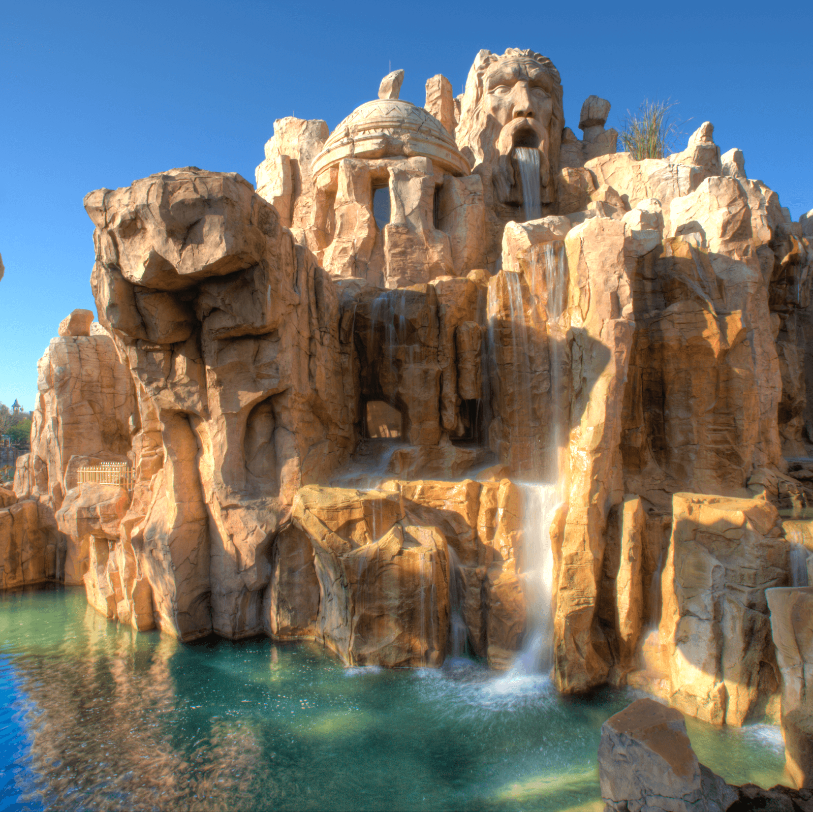 Una cara y cascada en la pared de esta estructura rocosa, al exterior del Mythos Restaurant en Universal’s Islands of Adventure.