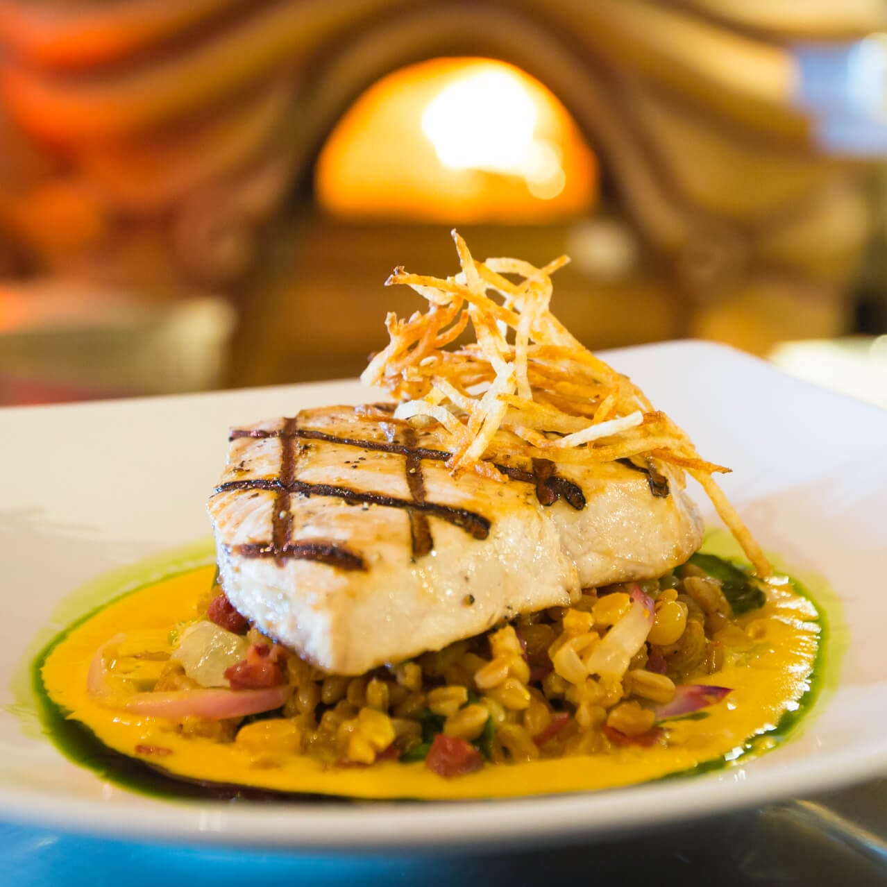 Un plato con pescado y vegetales de Mythos Restaurant.
