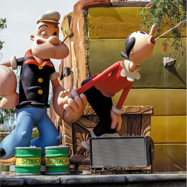 Una estatua caricaturizada de Popeye el marino, sus emblemáticas latas de espinacas y Olive Oyl en Popeye & Bluto's Bilge-Rat Barges en Universal's Islands of Adventure.
