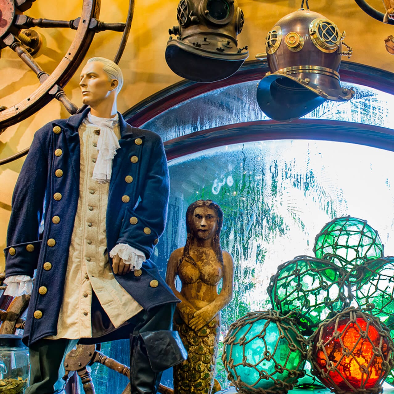 Un maniquí vestido con un uniforme de capitán, un antiguo casco de buceo y la estatua de una sirena son algunas de las antigüedades náuticas que puedes encontrar en Islands of Adventure Trading Company, en Orlando.