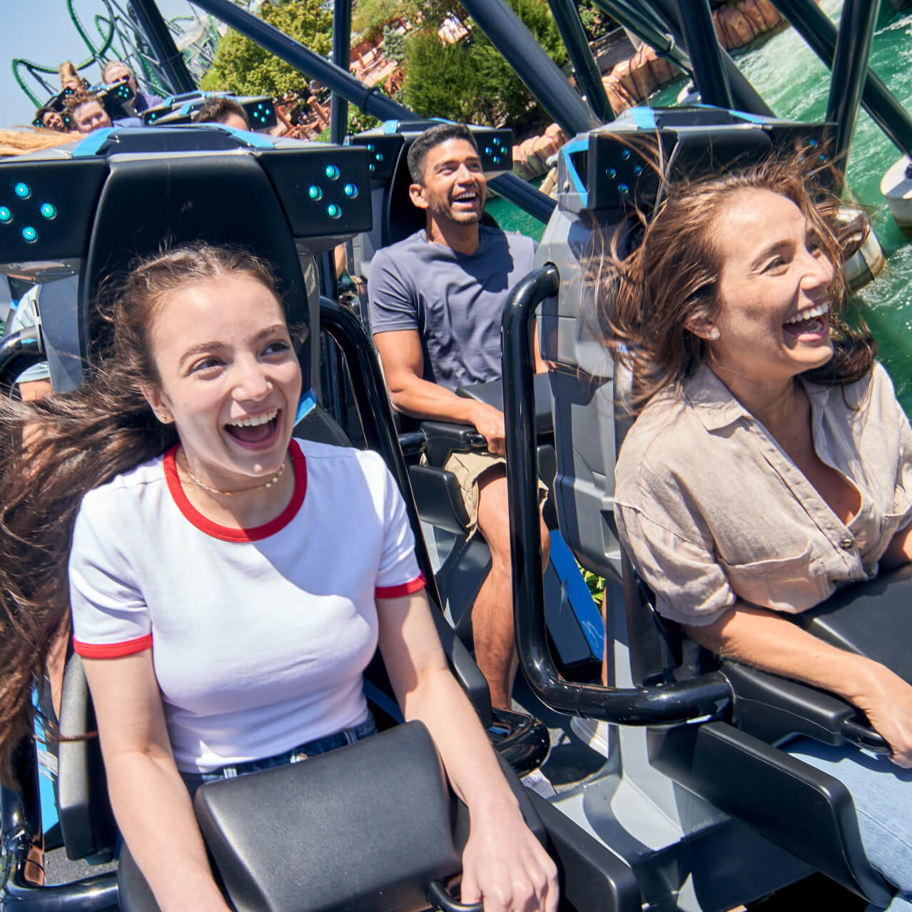 An&nbsp;excited&nbsp;family&nbsp;laughing&nbsp;and&nbsp;holding&nbsp;on&nbsp;tight&nbsp;as&nbsp;their&nbsp;coaster&nbsp;vehicle&nbsp;rolls&nbsp;through&nbsp;a&nbsp;turn&nbsp;over&nbsp;water.