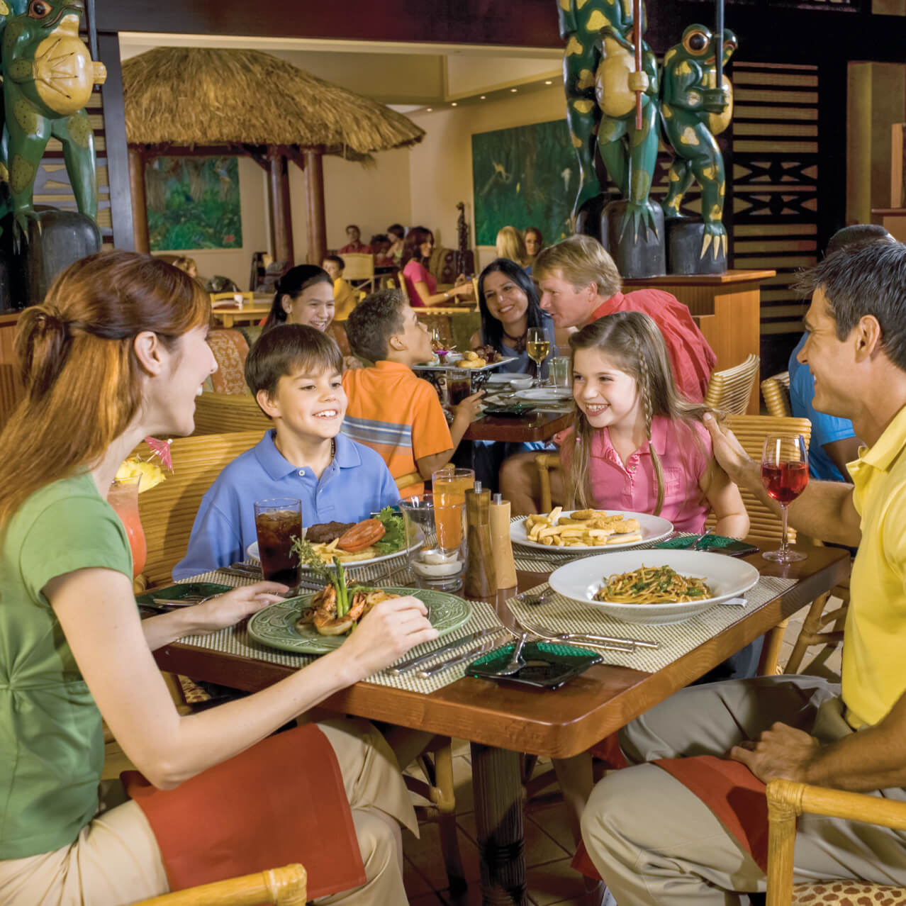 Dos padres con dos niños se sientan juntos para cenar en Islands Dining Room, en Loews Royal Pacific Resort.