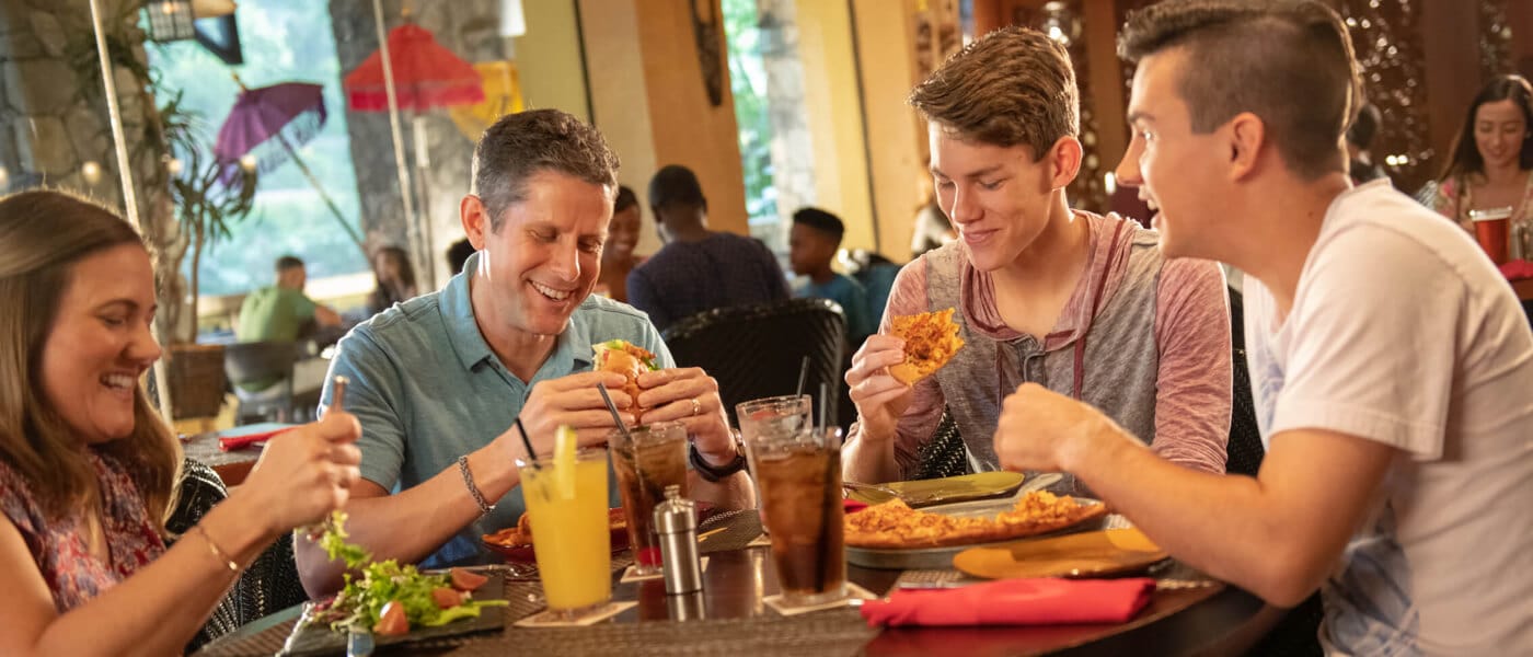 Un grupo de visitantes disfruta de comida y bebidas en Jake's American Bar en Loews Royal Pacific Resort.
