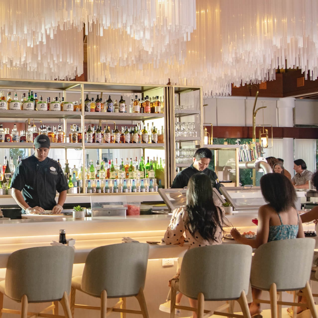 Chefs en Orchid Court Lounge and Sushi Bar preparando sushi frente a los visitantes.