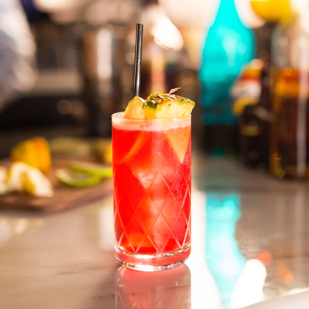 Una bebida tropical mezclada con una rebanada de piña te espera en el mostrador en el Strong Water Tavern dentro de Loews Sapphire Falls Resort en Universal Orlando.