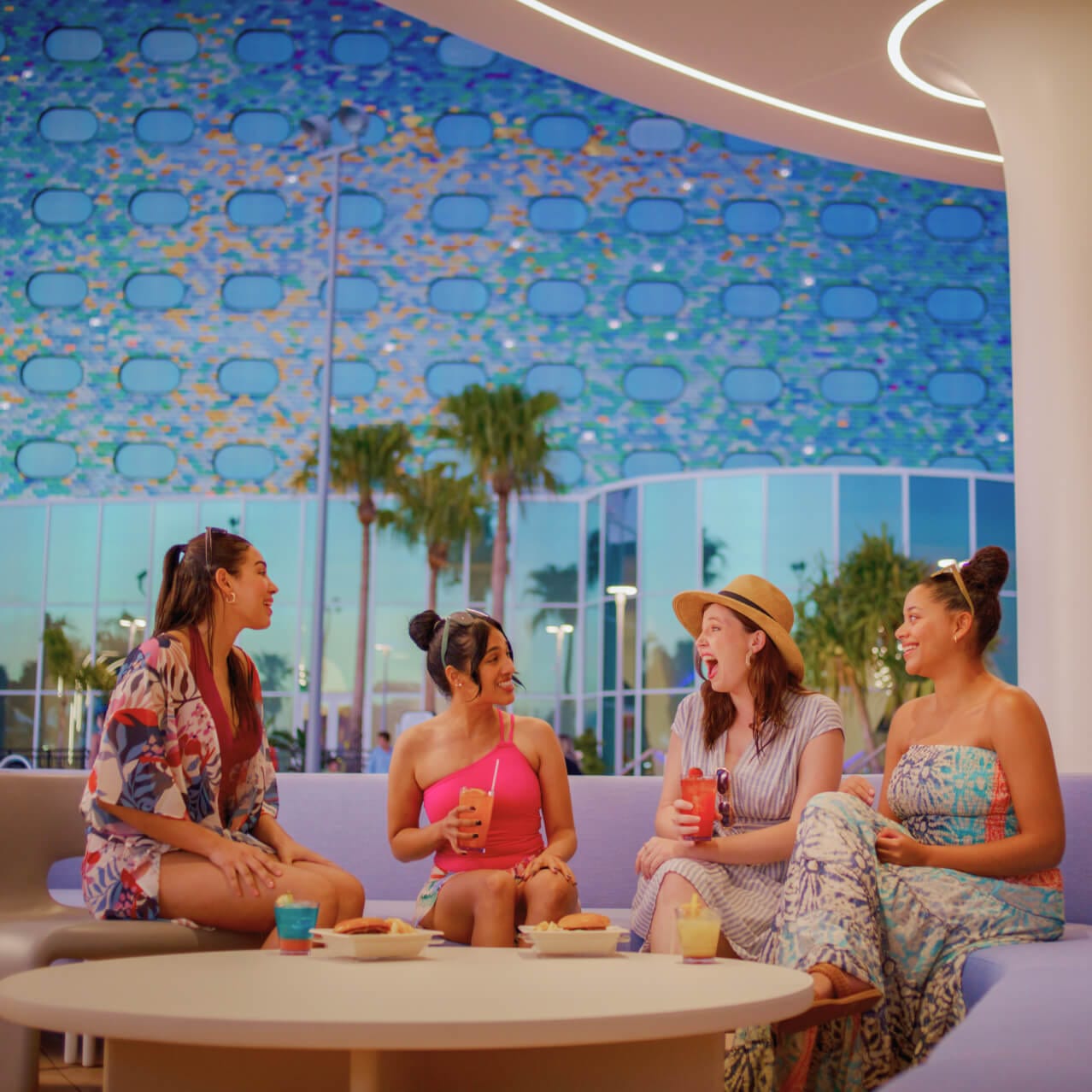 Amigos sentados juntos disfrutan de unas bebidas junto a la piscina en Galaxy Bar y Galaxy Grill en Universal Stella Nova Resort.