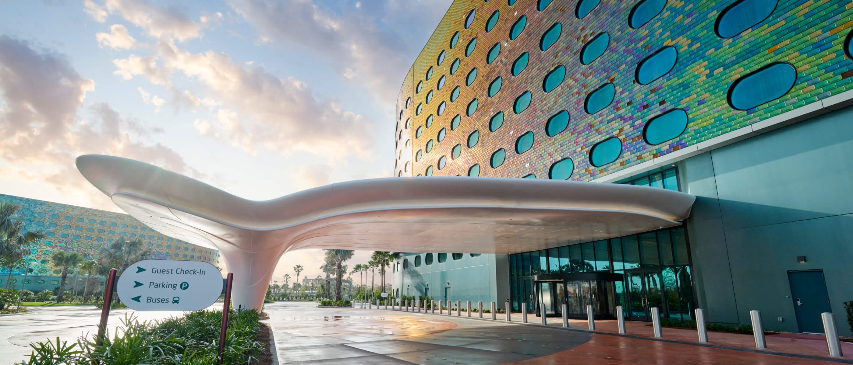 La entrada principal con forma futurista de Universal Terra Luna Resort, con la fachada del hotel resplandeciente bajo la luz del sol.