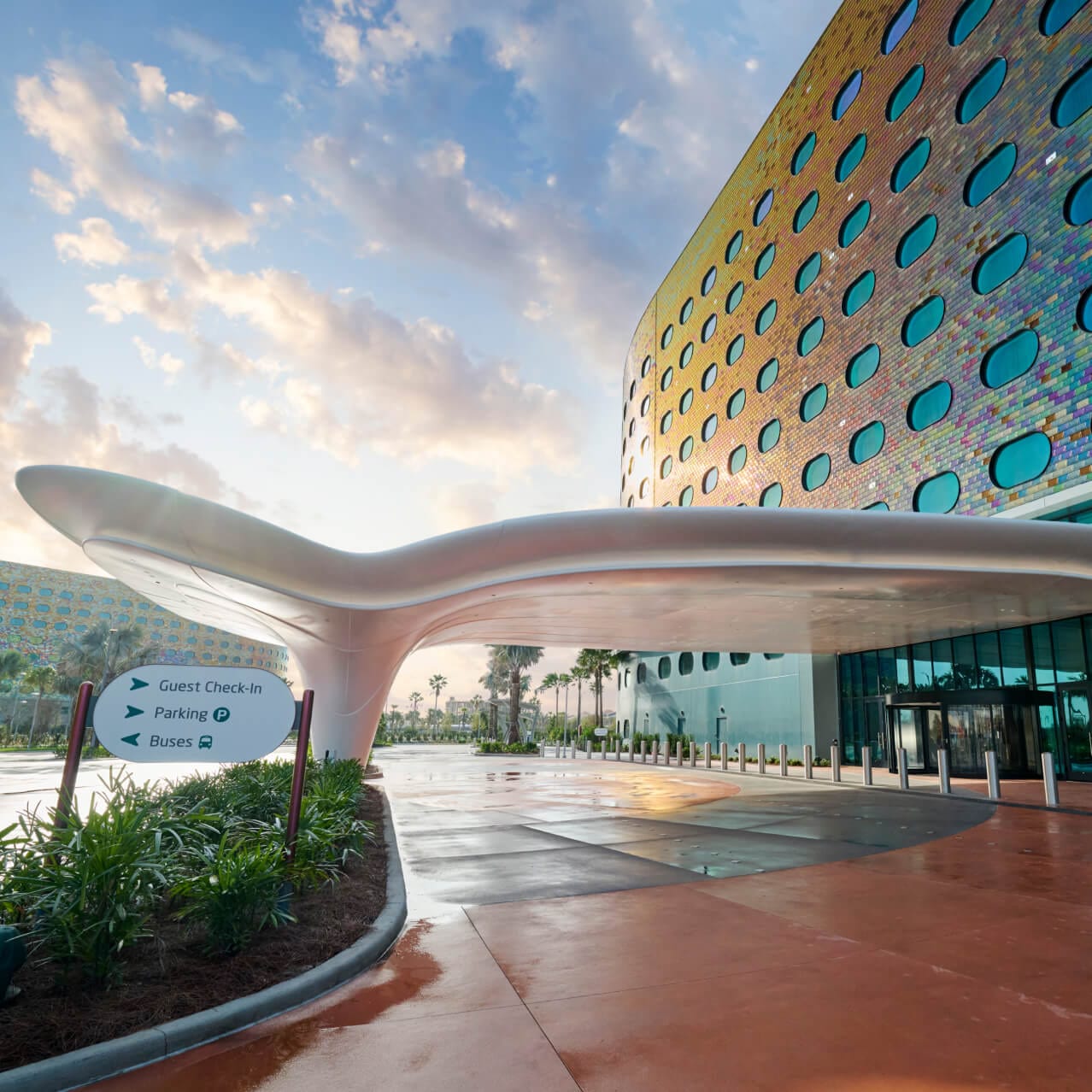 La entrada principal con forma futurista de Universal Terra Luna Resort, con la fachada del hotel resplandeciente bajo la luz del sol.
