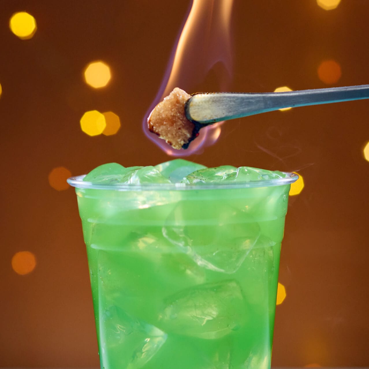 Meteor Strike, un coctel de ron teñido de verde con un terrón de azúcar infusionado con extracto de limón flameante, servido en Bar Zenith en Celestial Park.