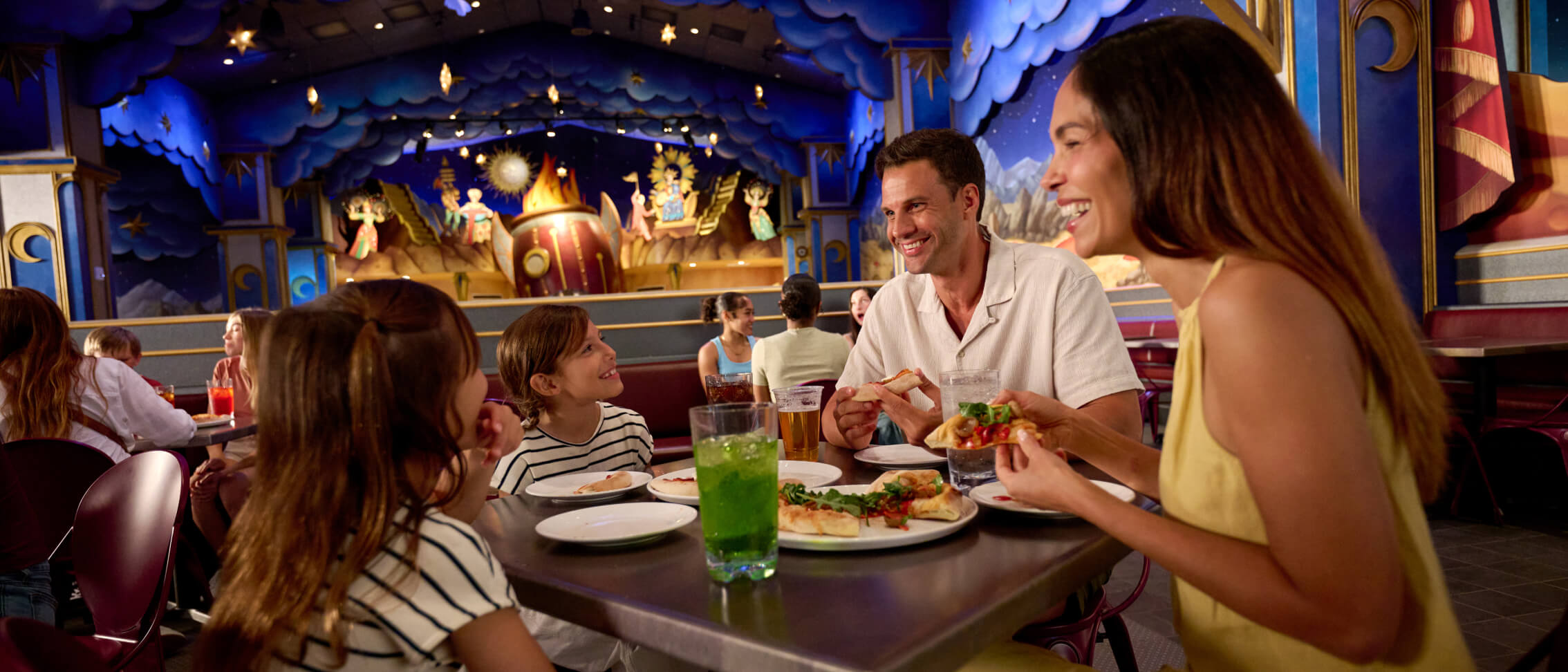A young family of four enjoys conversation over pizza and beverages at Pizza Moon inside Celestial&nbsp;Park.