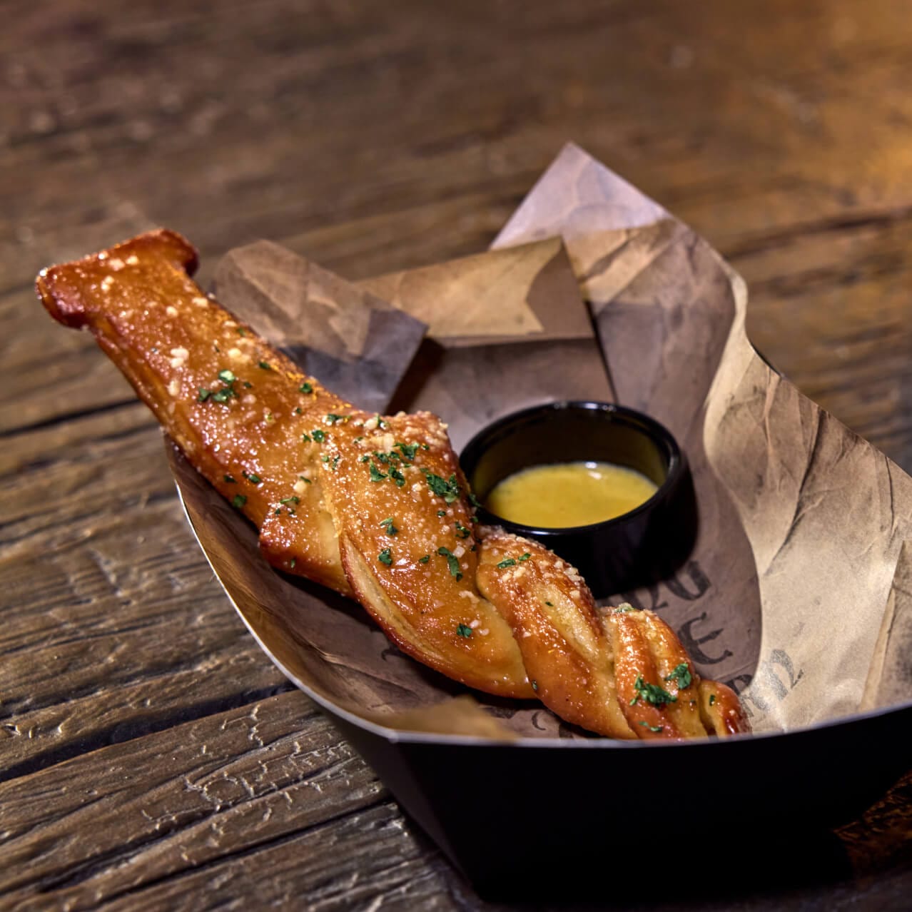 Hunter's Garlic Stake, un pretzel crujiente con mantequilla de ajo y salsa de ajo, servido en The Burning Blade Tavern.