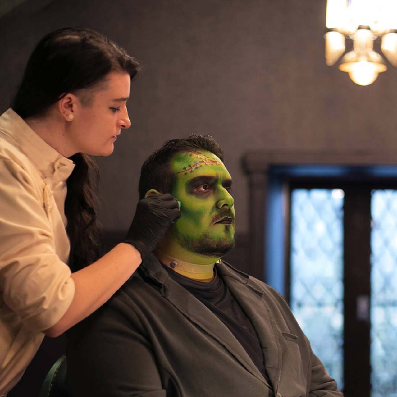A skilled artist of Darkmoor Monster Makeup Experience works on a customer's face makeup, transforming him into Frankenstein's monster.