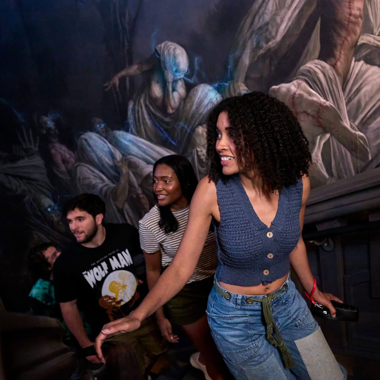 Visitantes subiendo cautelosamente las escaleras en la fila de la atracción Monsters Unchained: The Frankenstein Experiment.