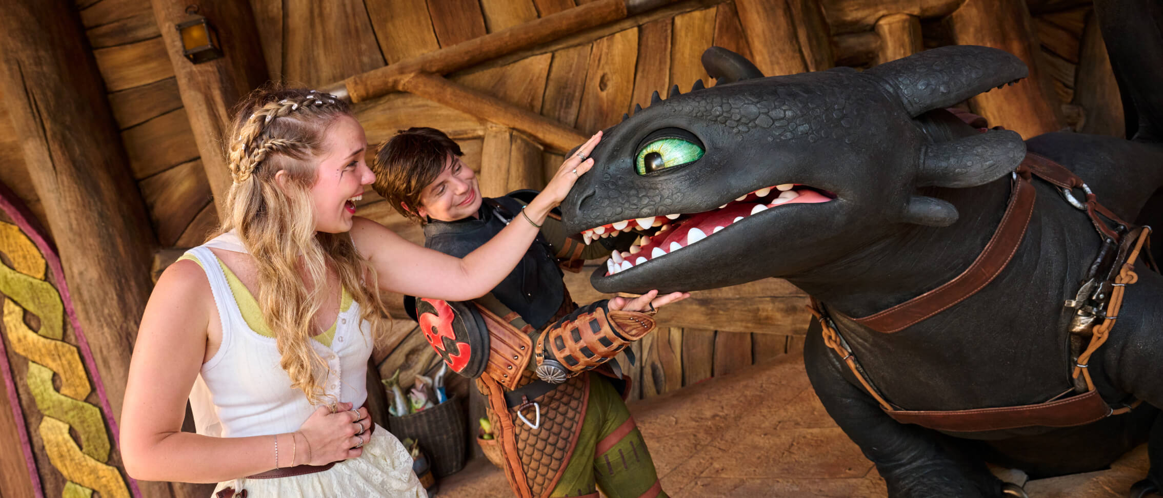 A guest pets Toothless' nose as Hiccup smiles down at Toothless during a Character Meet & Greet at How to Train Your Dragon - Isle of Berk.