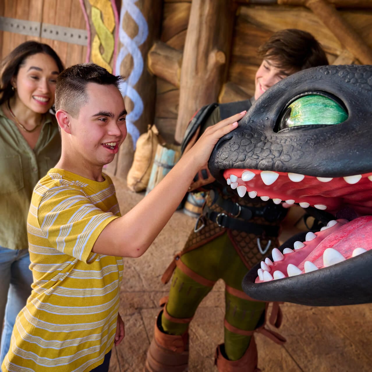 Excited Guests enjoying an up-close meet and greet with Toothless as one reaches out to touch the dragon’s face.