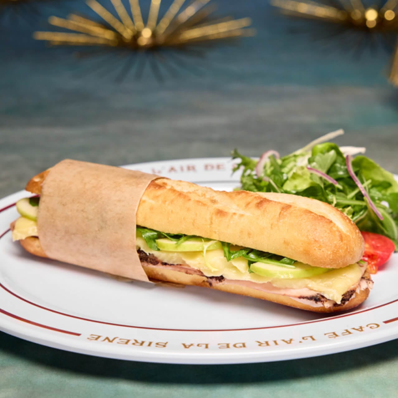 El Baguette de Dinde consta de rodajas de pavo con pimienta negra molida, manzanas, queso brie y rúcula, cubierto con mantequilla de mostaza y mantequilla de manzana servido en un baguette crujiente y caliente de Café L’air De La Sirène.