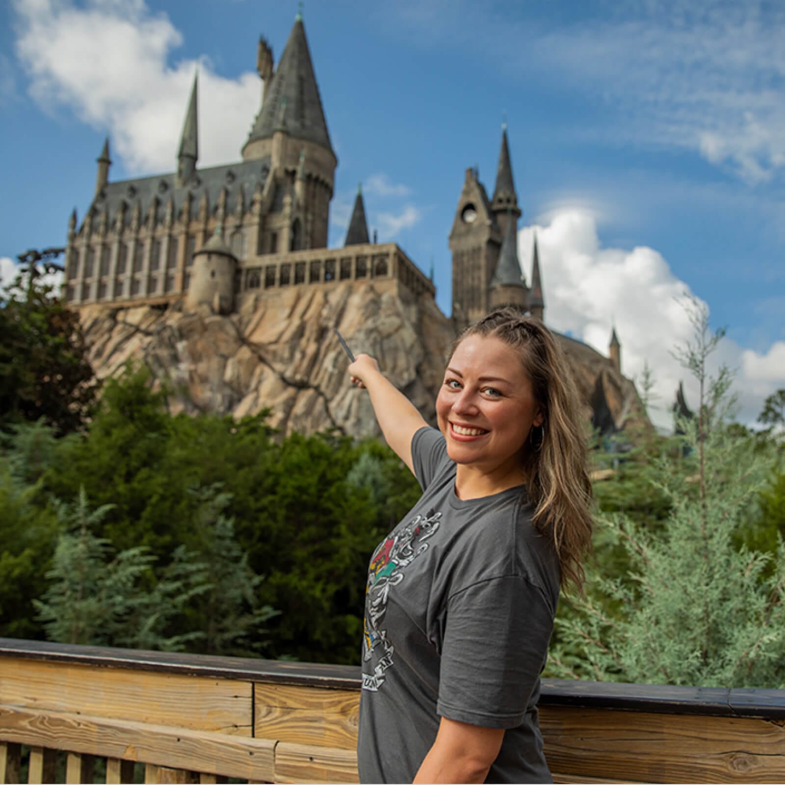 Una visitante tomándose una foto mientras apunta detrás al Castillo Hogwarts™.
