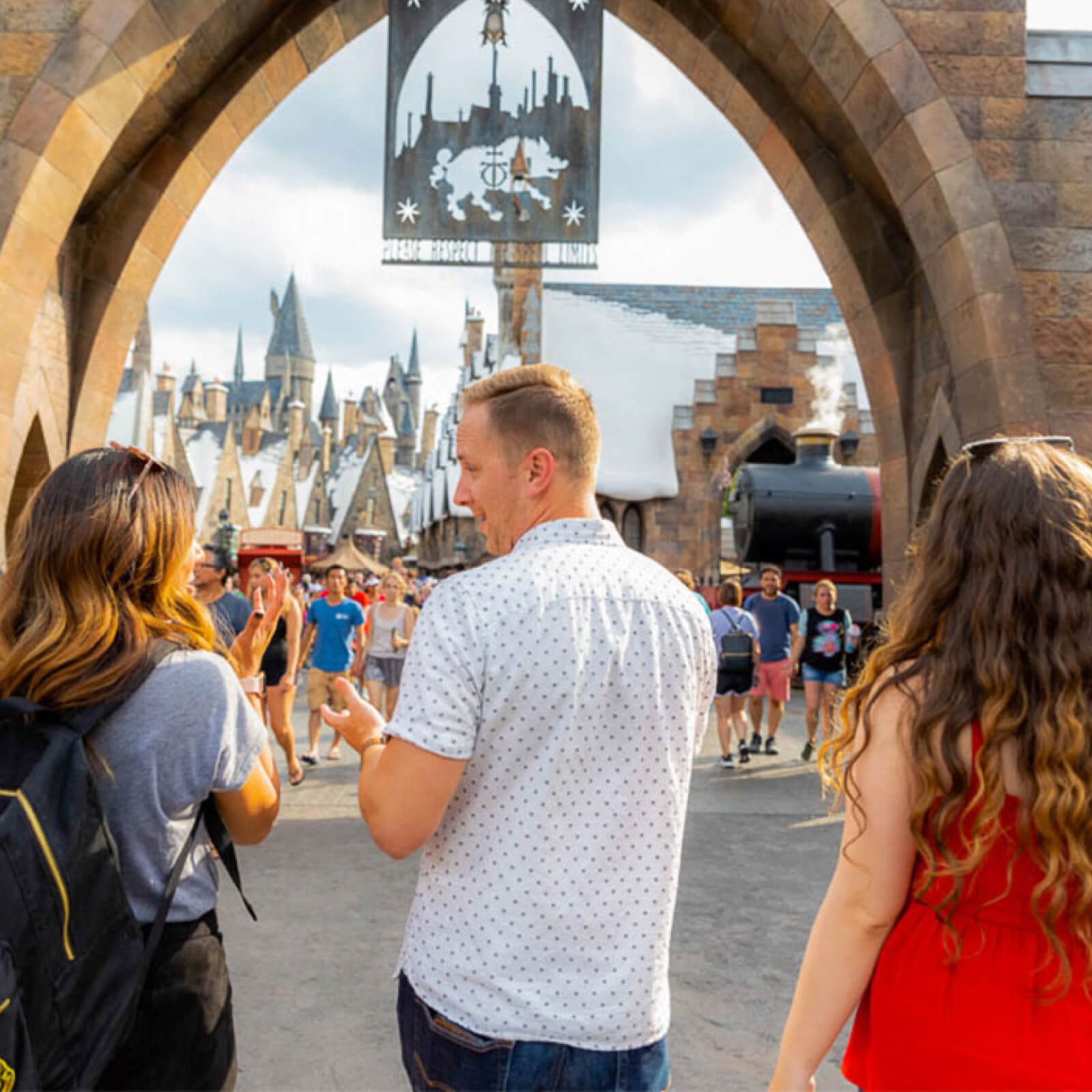 Tres amigos caminando hacia la entrada de The Wizarding World of Harry Potter™.