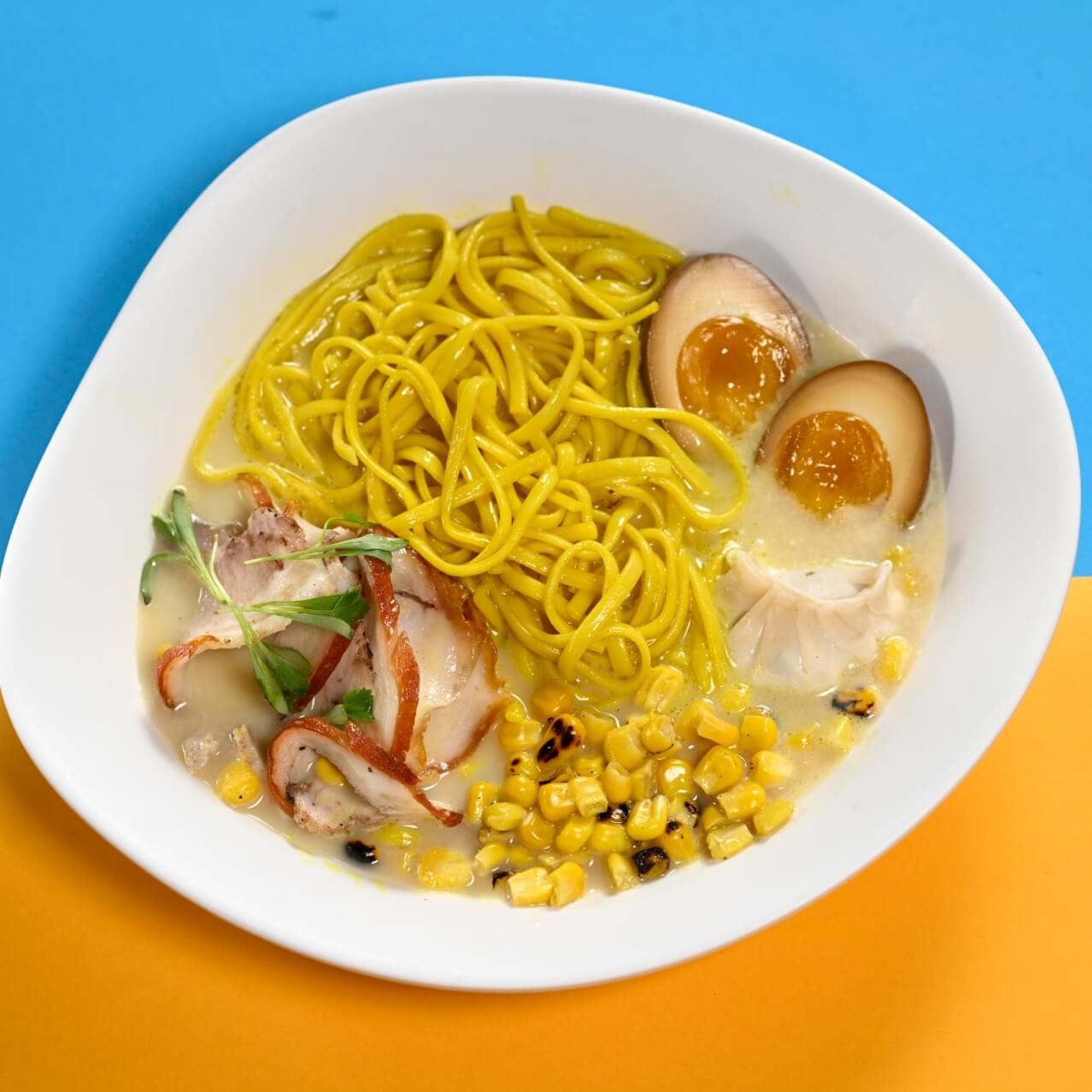 El Otto’s Noodle Bowl sobre un fondo amarillo y azul claro.