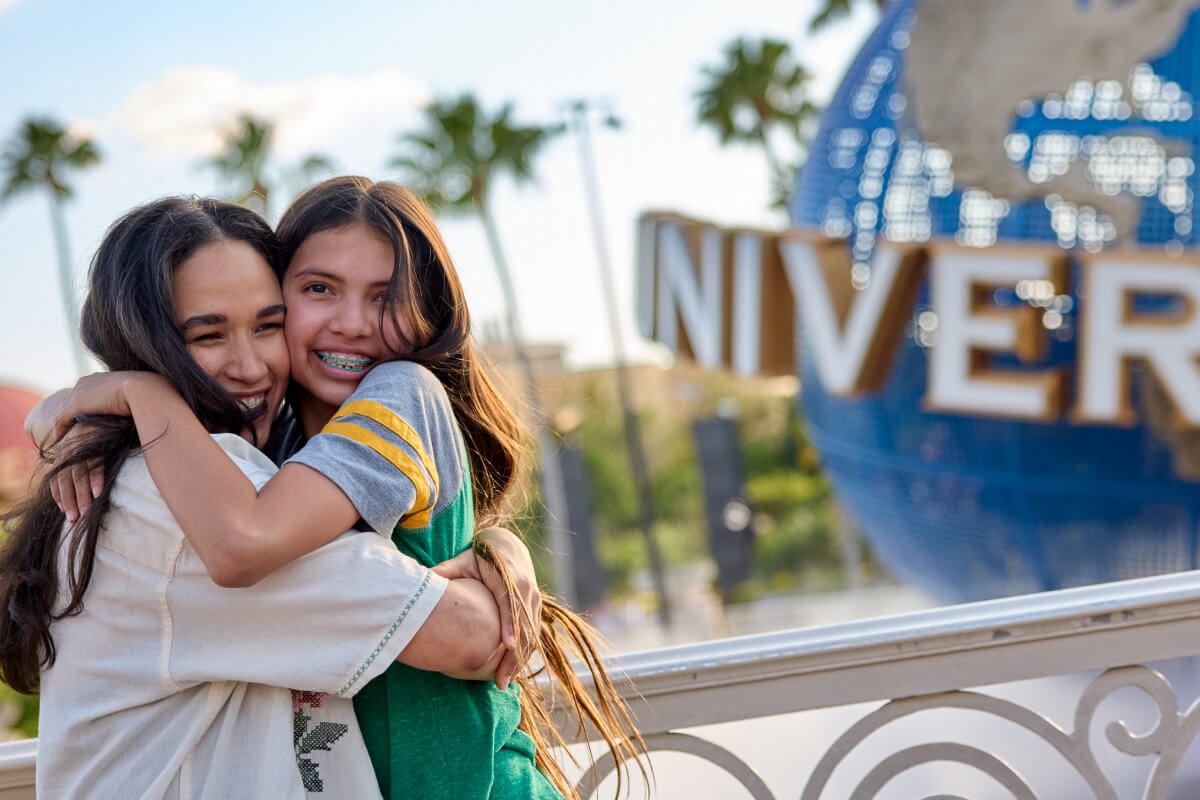 Madre e hija abrazándose y sonriendo frente al icónico globo de Universal.
