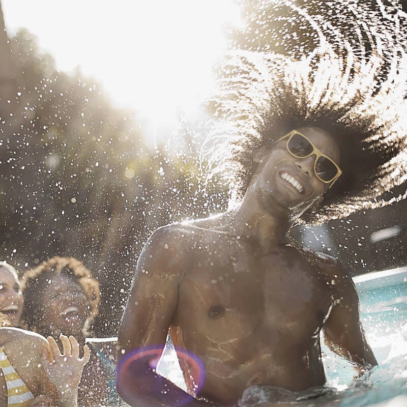 Un hombre agita el cabello en la piscina con sus amigos