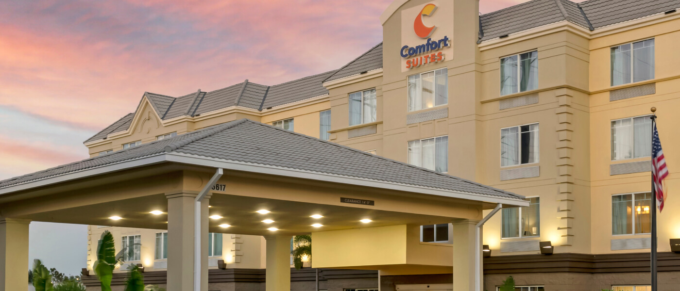 A pink and blue sunset over the front entrance of the Comfort Suites Near Universal Orlando Resort.
