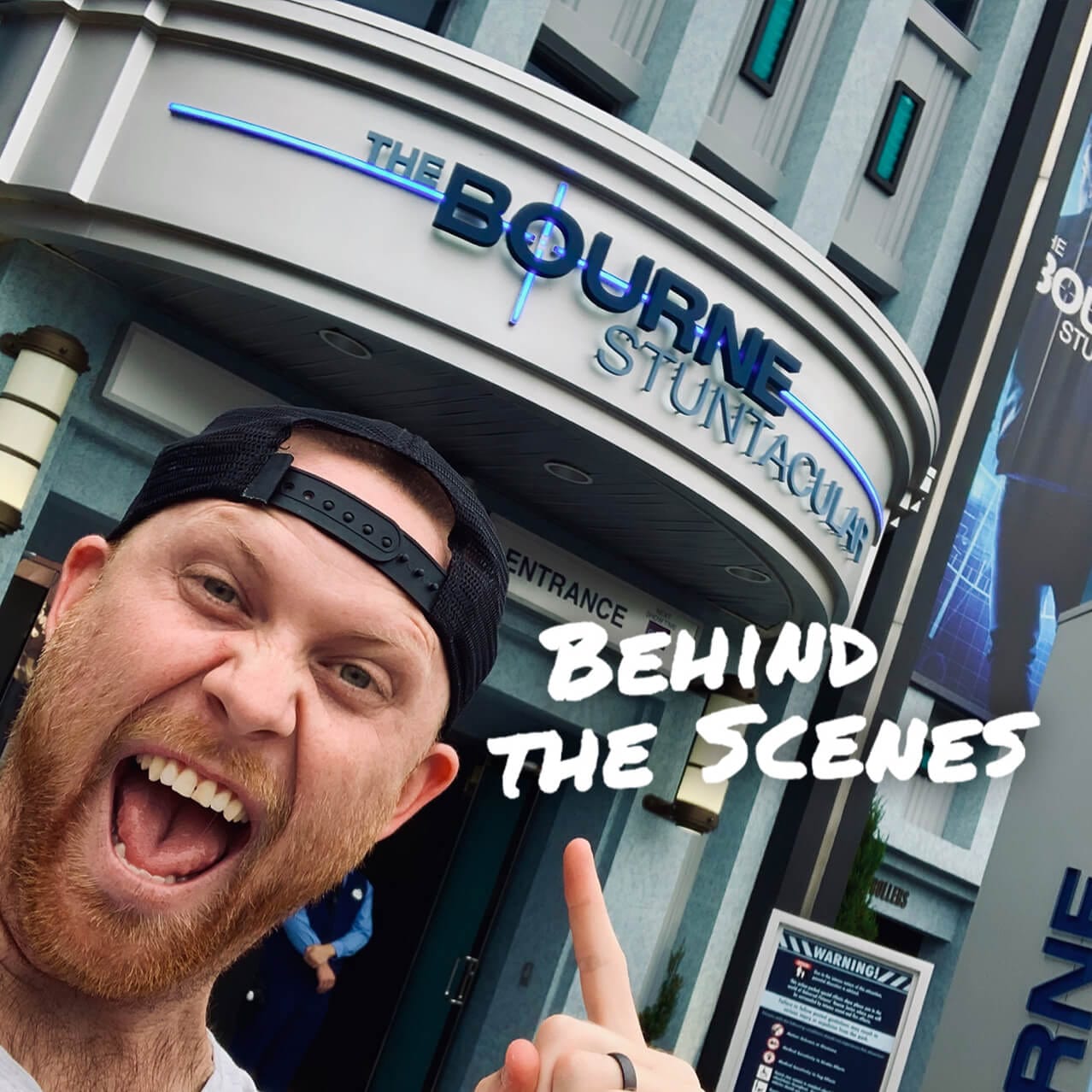 La fachada de The Bourne Stuntacular con el anfitrión del video detrás de las escenas sonriendo frente al texto “Tras Bastidores”.