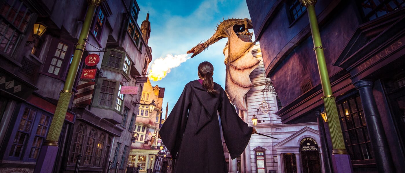 Una niña con una toga de hechicera, frente al dragón que lanza una llama de fuego en Diagon Alley, de Universal Studios Florida.