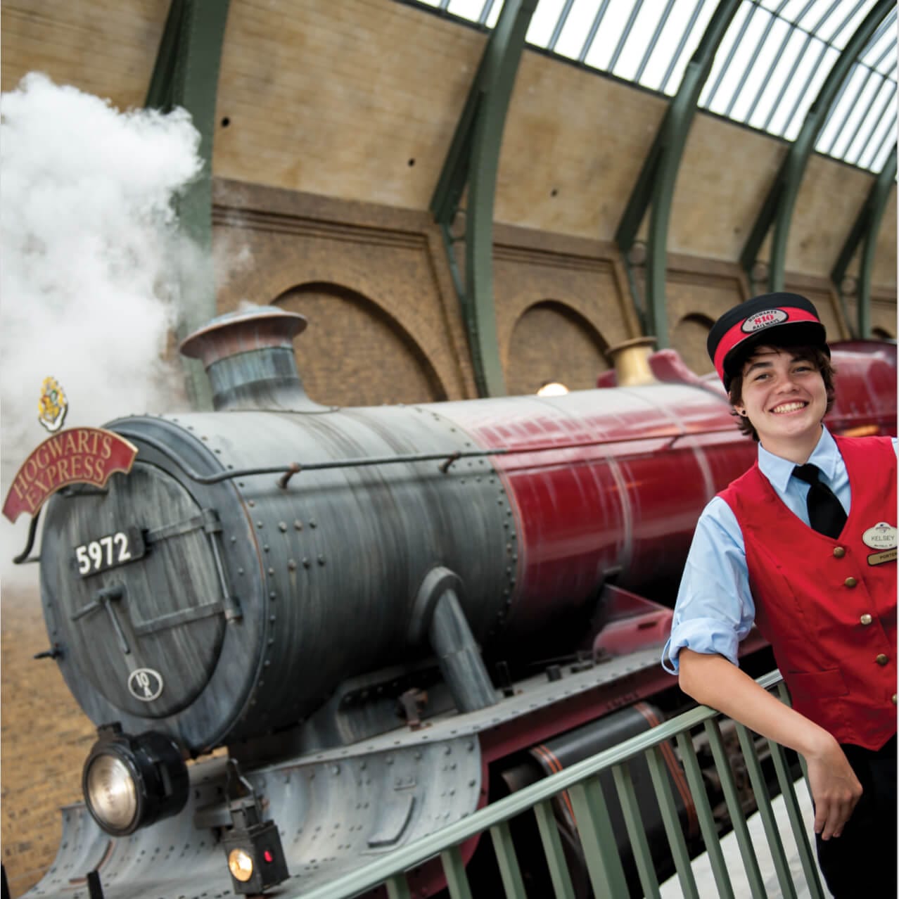 Un miembro del personal de la estación, saluda a visitantes del viaje en tren Hogwarts™ Express con temática de Harry Potter en Universal's Islands of Adventure en Orlando.