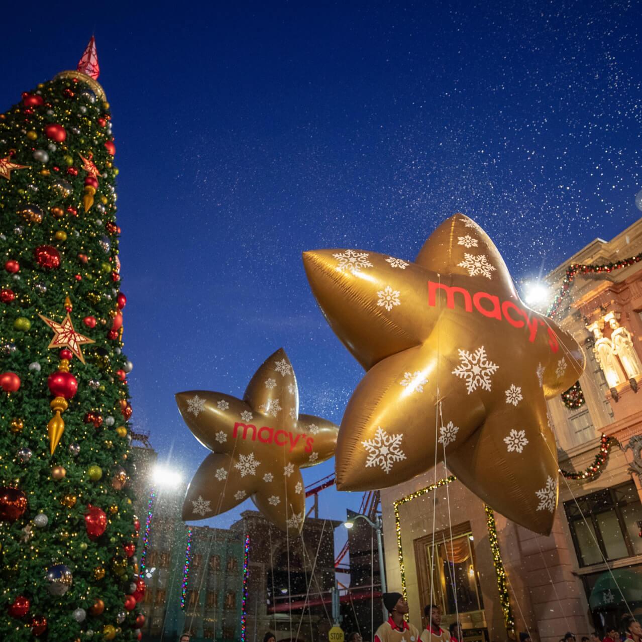 Los globos de estrellas de Macy's en Universal Studios Florida pasan por un árbol gigante decorado por la temporada festiva.