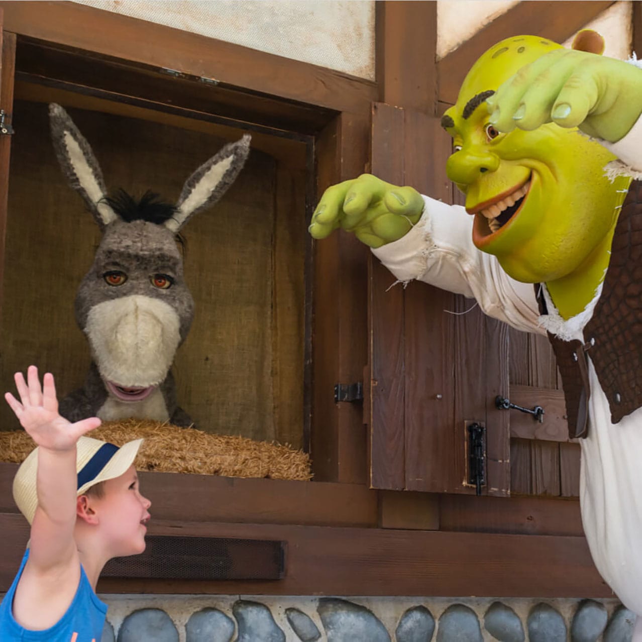 Un padre y su hijo interactúan con Shrek y Donkey en el área de encuentros con el famoso dúo en Universal Studios Orlando.