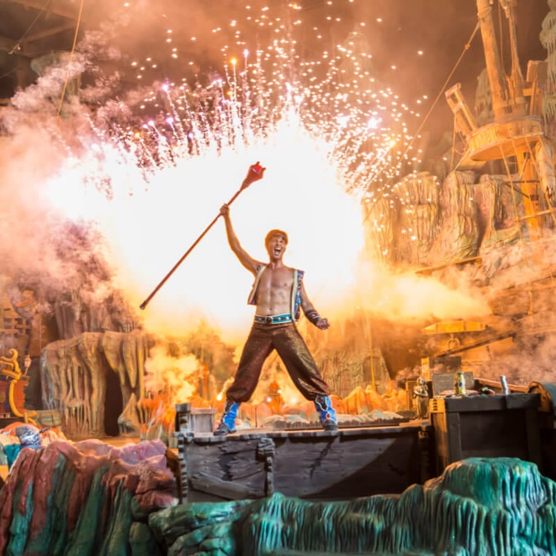 Un actor levanta un bastón sobre su cabeza al mismo tiempo que algo hace explosión detrás de él, durante The Eighth Voyage of Sindbad Stunt Show en Universal Orlando.