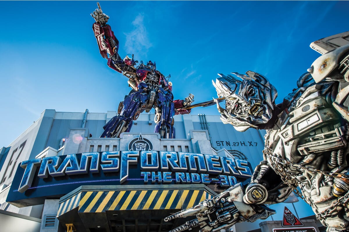Megatron se para frente a una estatua de Optimus Prime en la entrada de TRANSFORMERS: The Ride 3D en Universal Studios Florida en Orlando. 