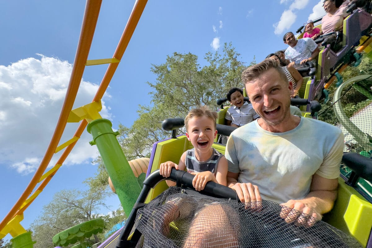 Visitantes sonriendo con entusiasmo mientras disfrutan de la montaña rusa Trollercoaster en DreamWorks Land.