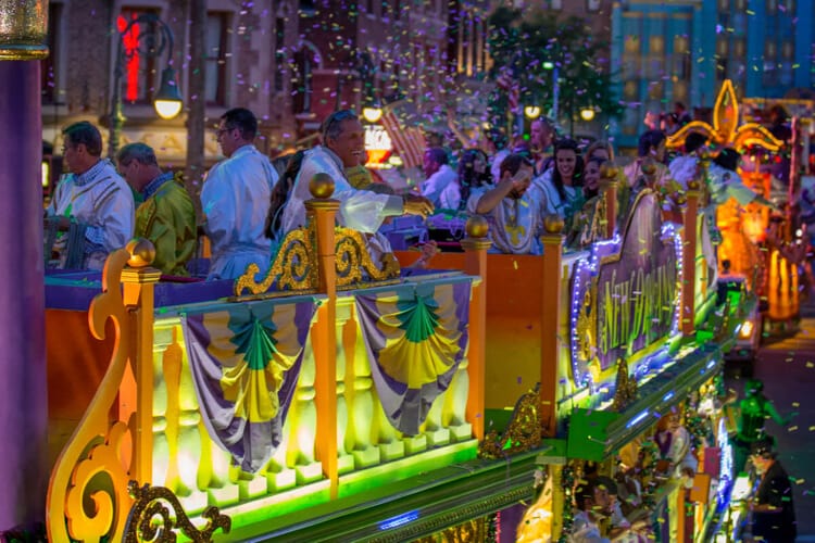 Visitantes lanzan collares a la multitud desde la cima de una carroza del desfile en Universal Mardi Gras: Carnaval de Sabores del Mundo.