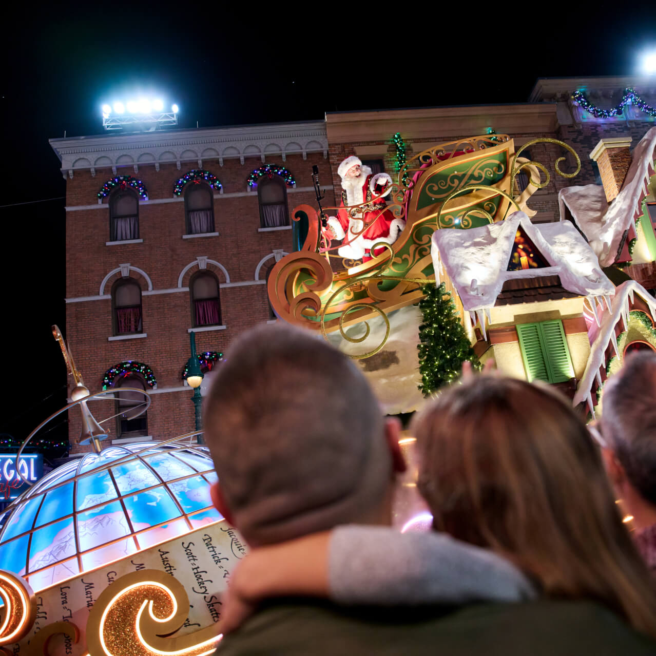 Personas observando la carroza de Santa en su trineo sobre un tejado durante las Navidades en Universal Orlando.