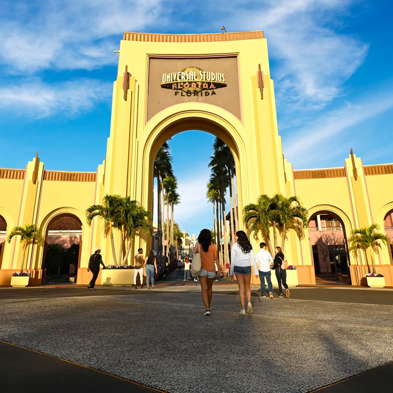 Personas caminando hacia el arco de entrada de Universal Studios Florida.