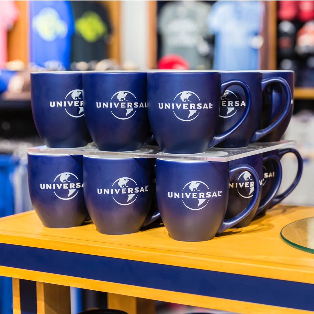 Tazas azules con el tema de Universal se exhiben en la tienda Universal Studios Store®.