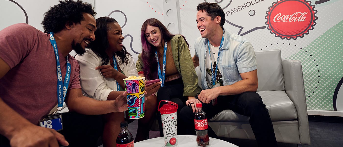 Una familia de cuatro Portadores de Pase sosteniendo Cokes en el UOAP Lounge.