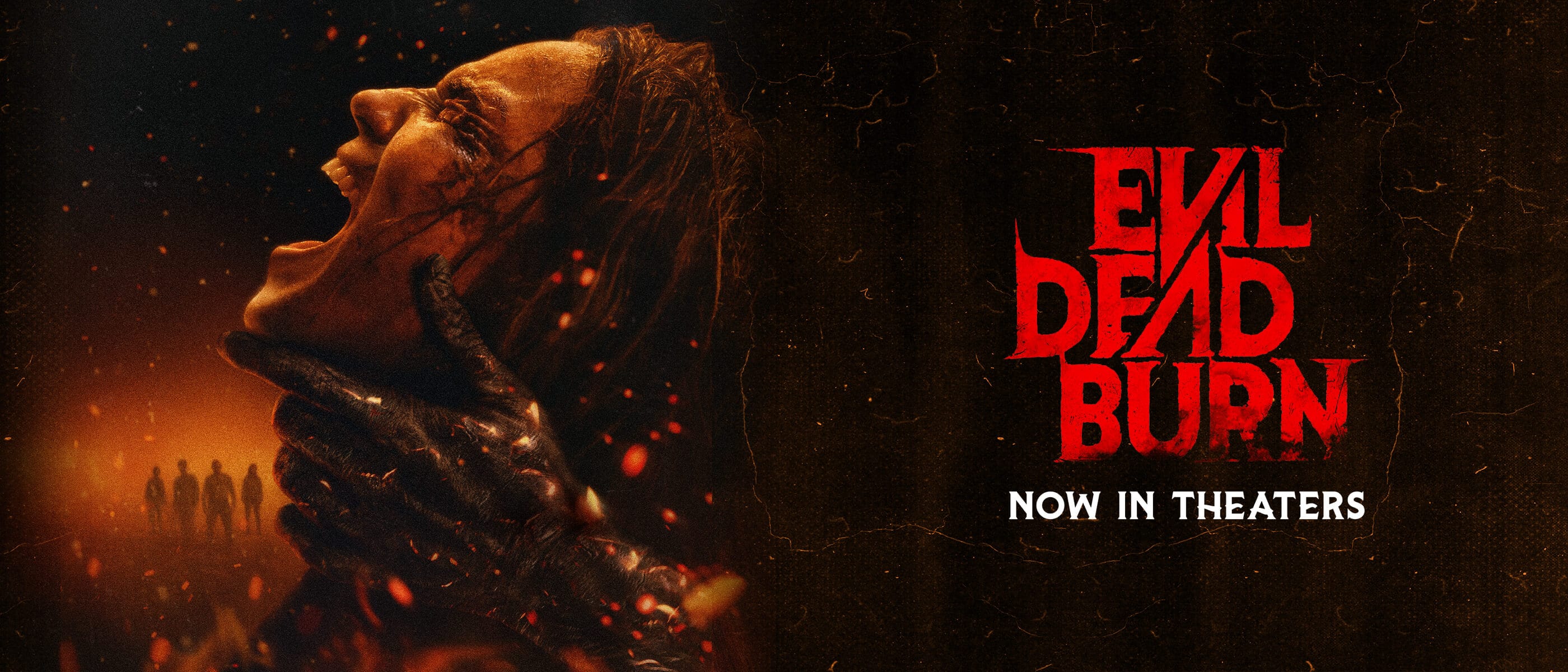 The Evil Dead Burn movie poster with a woman engulfed in flames as hands grip her neck and the text: Now in Theaters.