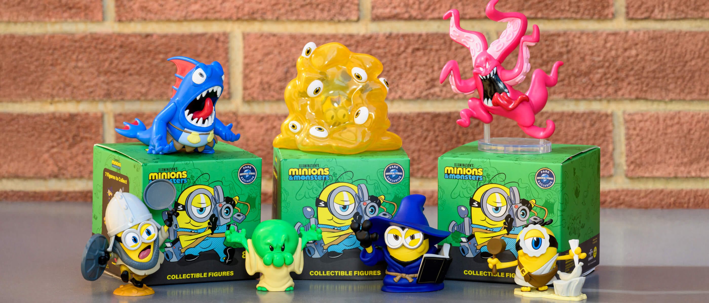 Various collectible figurines of colorful characters from Minions & Monsters with the green boxes they come in.