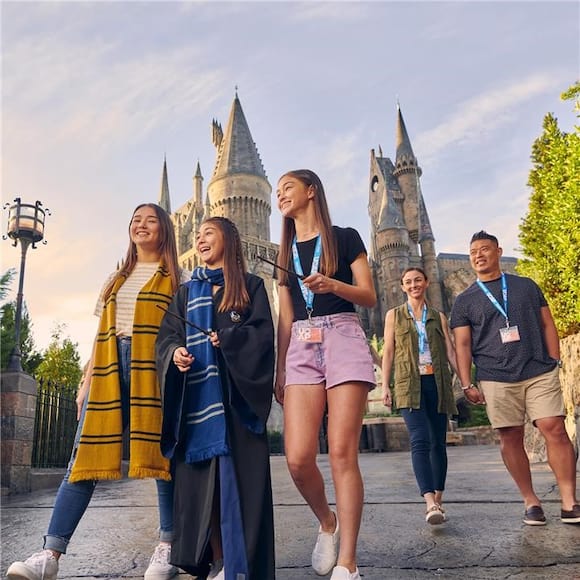 Un grupo de Portadores de Pase con sus varitas mágicas frente al castillo Hogwarts™, en Universal's Islands of Adventure