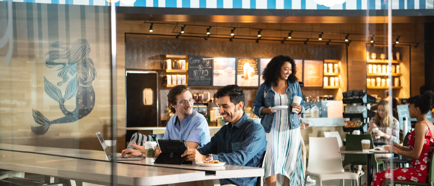 Amigos tomando um café juntos enquanto trabalham em seus laptops no Starbucks do Universal's Aventura Hotel.