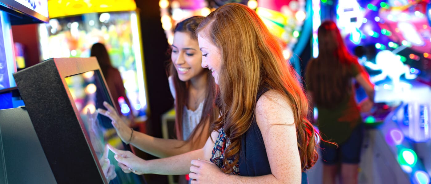 Duas meninas brincam com uma tela sensível ao toque dentro do animado fliperama Game-O-Rama no Universal's Cabana Bay Beach Resort.